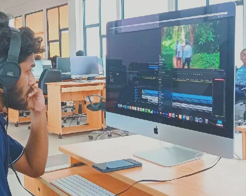 A Video Editor sitting in front of a computer with headphones on.